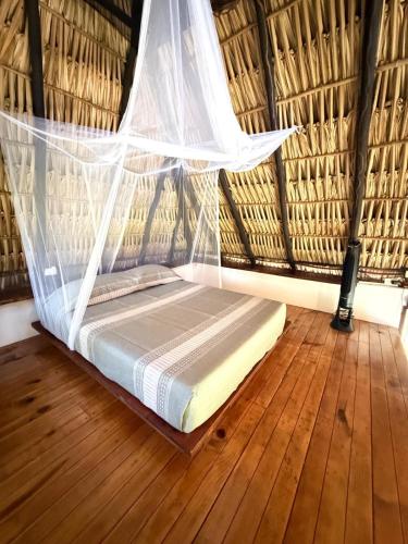 a bed in a thatched room with a net at Loft Amplio con Vista Natural en Mazunte in Mazunte