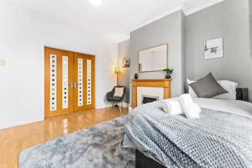 a white bedroom with a bed and a fireplace at Comfortable 4 Bed Home - Free Parking & Brand New Bathroom in Denton