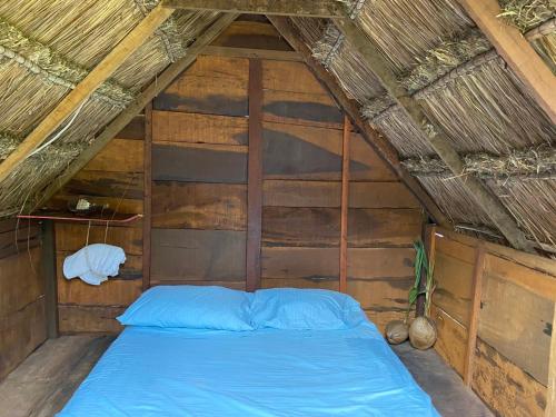 a bed in a wooden room with a roof at Hostalito Lahar in Bacalar
