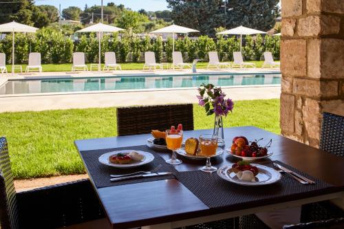 Ein Tisch mit Speisen und Getränken neben einem Pool in der Unterkunft B&B Le Bianche in Noci
