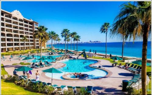 a pool at a resort with palm trees and the ocean at Oceanfront hideaway at Sonoran Spa N608 in Puerto Peñasco