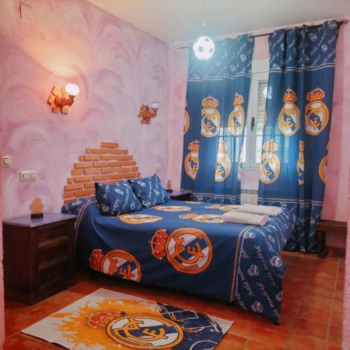 a bedroom with a bed with blue and orange sheets at Don Mauricio y periquines in Robledillo