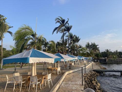una fila di tavoli e sedie con ombrelloni su una spiaggia di Songon Park Resort a Songon-Agban