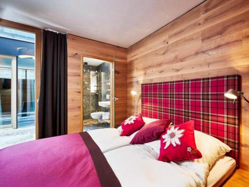 a bedroom with a large bed with red pillows at Smaragdresort Gipfelstürmer in Brandberg