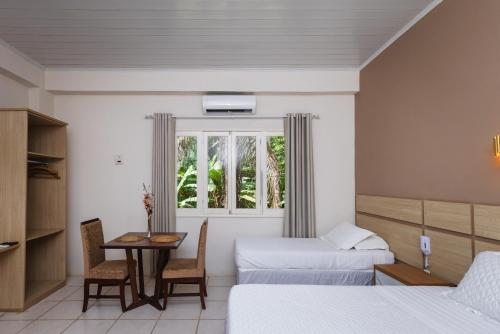a hotel room with two beds and a table and chairs at Hotel SPA Paraíso in Cruzeiro do Sul