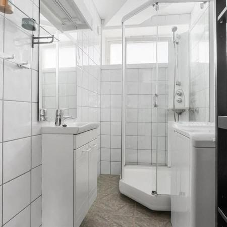 a white bathroom with a shower and a sink at Central 4 room apartment in Bergen