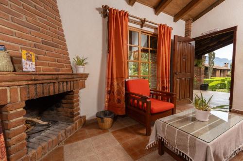 a living room with a brick fireplace and a red chair at Cabañas Sierra Verde in Cedro