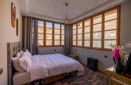 a bedroom with a bed in a room with windows at Riad dreams imlil in Imlil