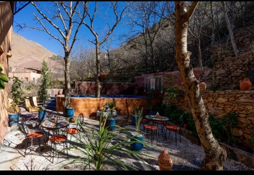 a patio with chairs and tables and a stone wall at Riad dreams imlil in Imlil