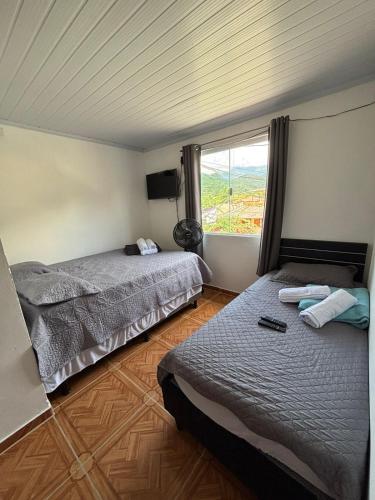 two beds in a room with a large window at Pousada Sol e Mar Dias Cezar in Paraty