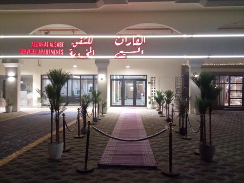 a lobby of a building with a sign and palm trees at ﻣﺆﺳﺴﺔ ﺷﻘﻖ ﺍﻟﻘﺎﺭﺍﺕ ﺍﻟﺴﺒﻊ ﺍﻟﻤﺨﺪﻭﻣﺔ in Raḩīmah