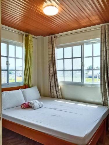a bedroom with a large bed with two windows at Rustic Retreat room only in San Fernando