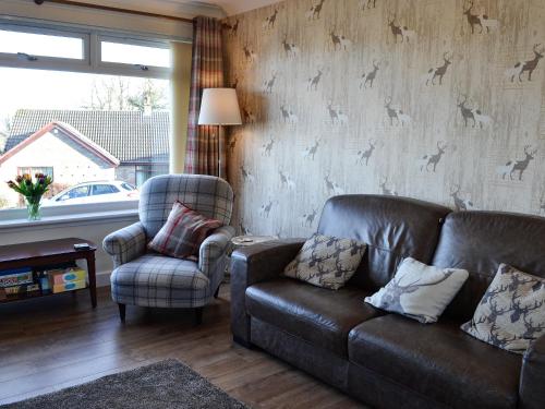 a living room with a leather couch and a chair at Glencairn Rd in Langbank