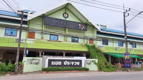a green building with a sign in front of it at แอทประจวบ-At Prachuap in Prachuap Khiri Khan