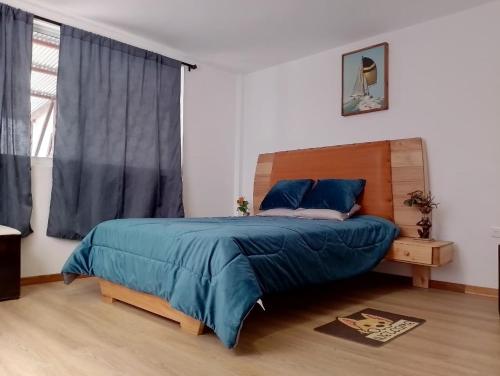 a bedroom with a bed with blue sheets and a window at Psi Nova in Baños