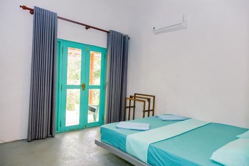 a bedroom with a bed and a green door at Lazy Monkey Green Chalets in Hiriketiya