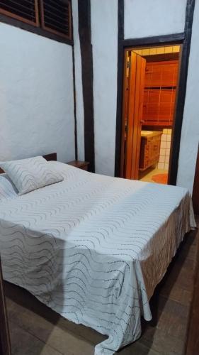 a white bed in a room with a window at Suite casa cachoeira in Paraty