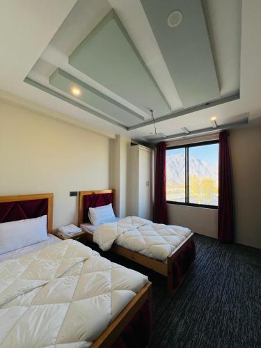 ein Hotelzimmer mit zwei Betten und einem Fenster in der Unterkunft Fialong Hotel Skardu in Skardu