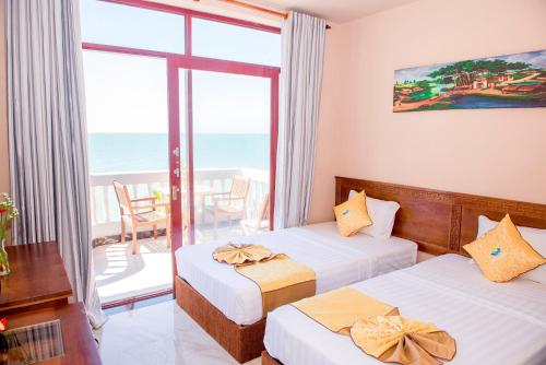 two beds in a room with a view of the ocean at Viva Beach Resort Mui Ne in Mui Ne