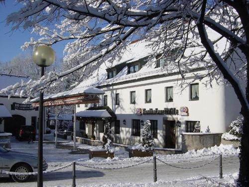 a large white building with snow on top of it at Hotel zur Mühle in Ismaning