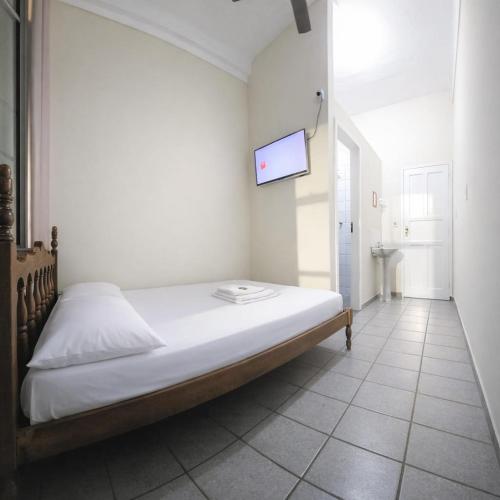 a bedroom with a bed with a tv on the wall at Estação Pousada e Hostel in Cataguases