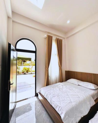 a bedroom with a bed and a large window at Max Home in Ninh Hải