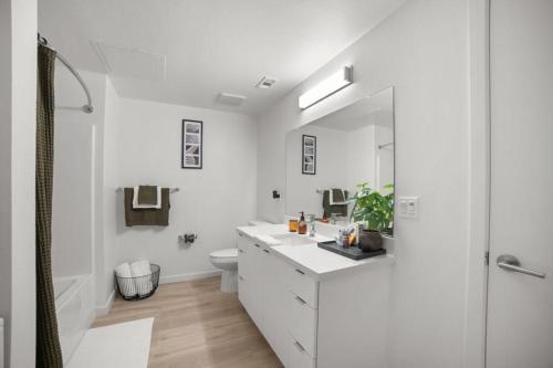 a white bathroom with a sink and a toilet at Modern Lux Midrise Stadium & Downtown Views in West Sacramento