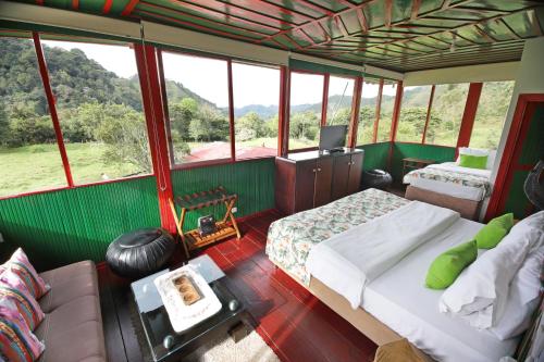 a room with two beds and a tv and windows at Finca La Playa Ecohotel - Experiencia Campestre - in Salento