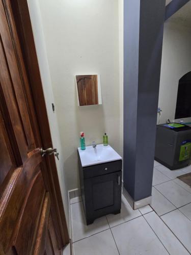 a small bathroom with a sink and a door at The Stone Way Suite in Juayúa
