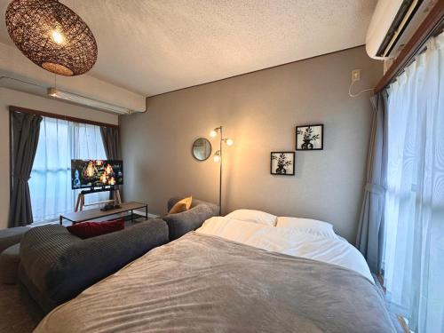 a bedroom with a bed and a couch at Villa Fuchu Stay in Fuchu