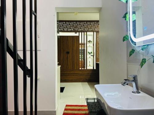 a bathroom with a sink and a hallway with a door at Nana's Residency, Cochin in Alwaye