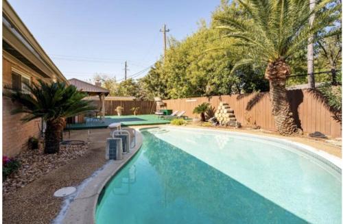 a swimming pool with palm trees next to a fence at Cozy Room with a Pool in Houston