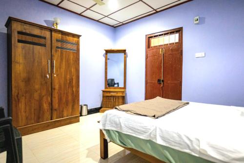 a bedroom with a bed and a wooden cabinet at Villa in Kalviyankadu in Irupalai