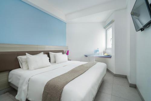 a bedroom with a large white bed and a television at JP Hotel Pluit Jakarta by LIFE in Jakarta