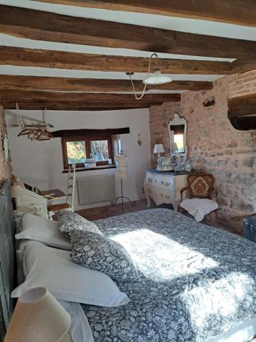 a bedroom with a bed and a stone wall at maison la Bambine chambre esprit château in Ozolles