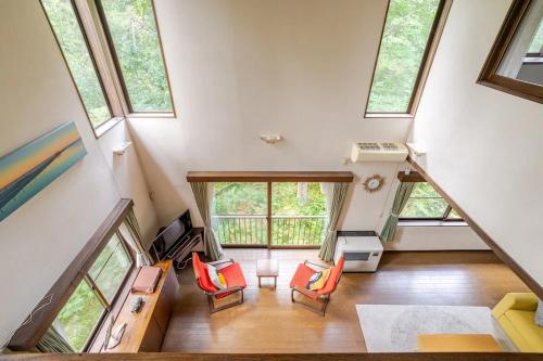an attic living room with four windows and orange chairs at Myoko Woodland Lodge in Myoko