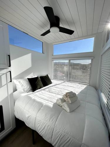 a bedroom with a large white bed with a ceiling fan at Joshua Tree Tiny Home - Remote & Modern Container Home on 5 Acres in Joshua Tree