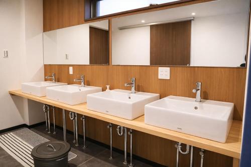 a bathroom with three sinks and a large mirror at Guest House Matsu in Osaka