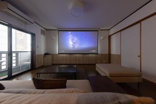 a living room with a large tv on the wall at Tabiudo Souwa in Takayama