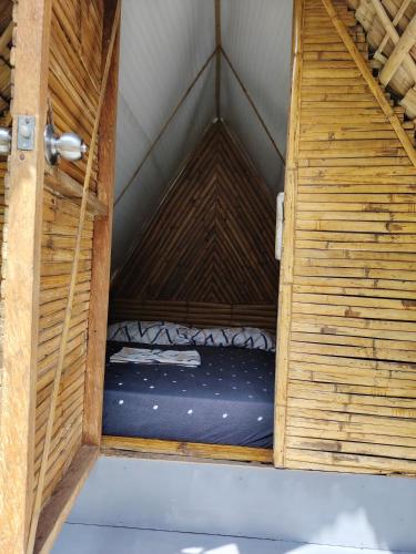 a small bed in a wooden room with a door at Bon Joy's Transient House in Mabini