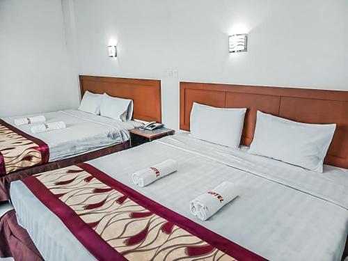two beds in a hotel room with two bedsskirts at New Palace Inn in Miri