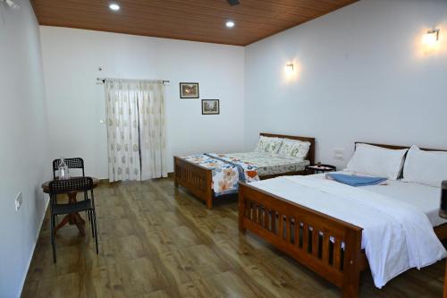 a bedroom with two beds and a table and a chair at Whispering Meadows By Dazzle Destinations - Coorg in Somvārpet