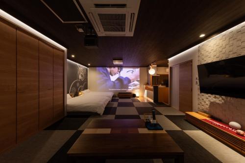 a bedroom with a bed and a tv on a wall at Tsuzumi Suite - Private Cinema & Immersive Stay in Kanazawa in Housai