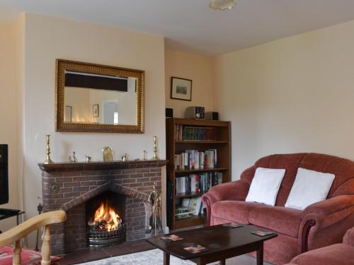 a living room with a fireplace and a mirror at Honeysuckle Cottage in Minsterley