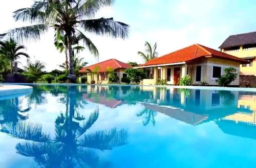 a swimming pool in front of a house at Diani modern Doric Cottages in Msambweni