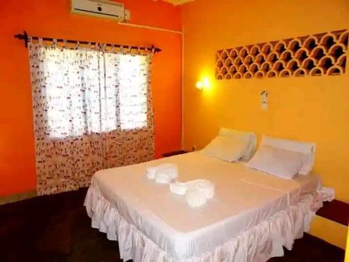 a bedroom with a bed with white pillows and a window at Diani modern Doric Cottages in Msambweni