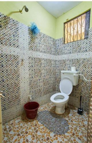 a tiled bathroom with a toilet and a window at Masai Apartments Diani in Ukunda