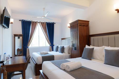 a hotel room with two beds and a desk at St Anthonys Holiday Inn in Kotagala