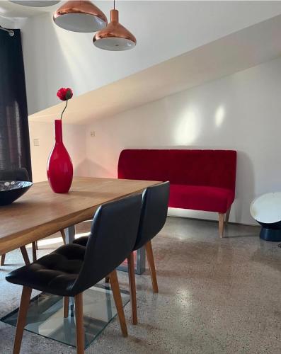 a red vase on a wooden table with a red couch at Maxhof Trier in Trier