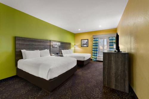 a hotel room with two beds and a television at Quality Inn Warrensburg in Warrensburg